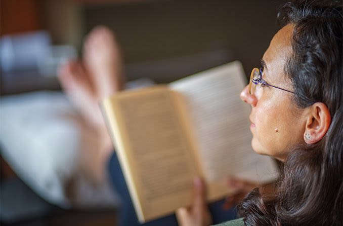 woman reading a book wearing reading glasses
