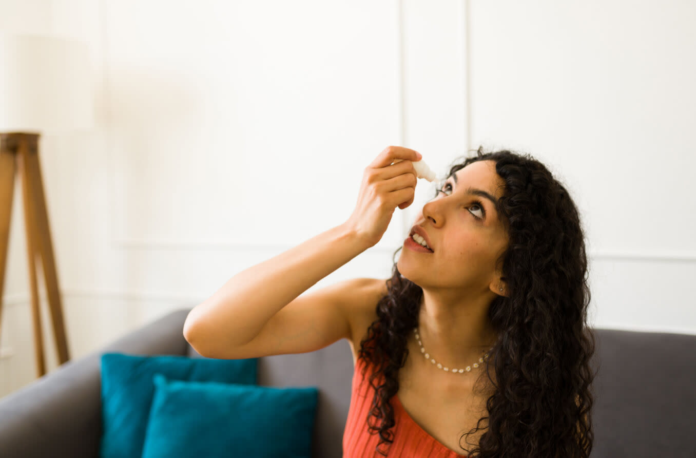 mujer usando gotas para los ojos para ayudar a blanquear sus ojos