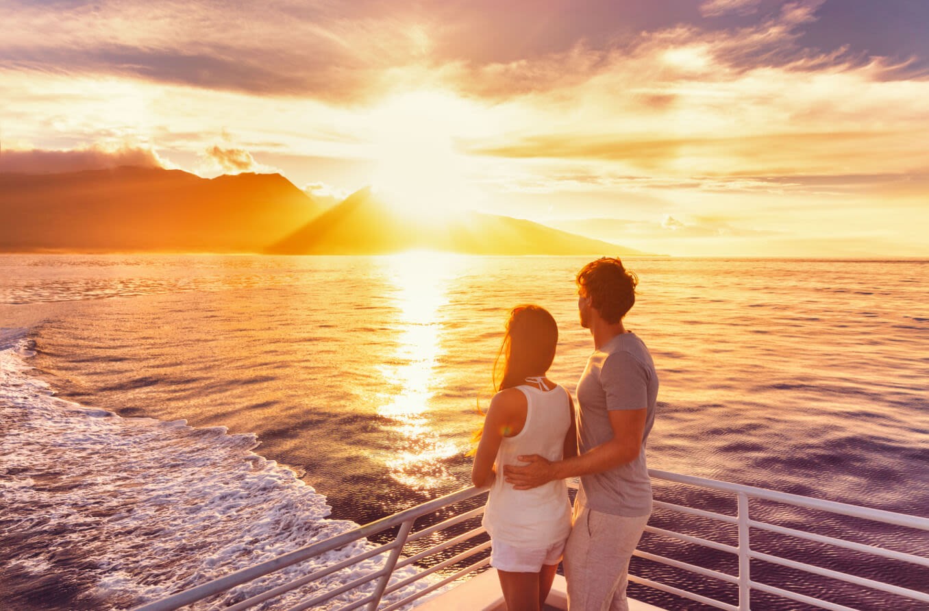 Couple standing AFT on a yacht, looking at the water.