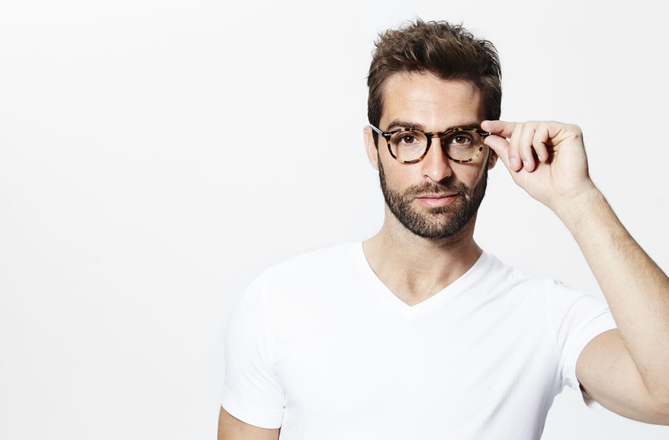 Bearded man wearing hat and glasses at night