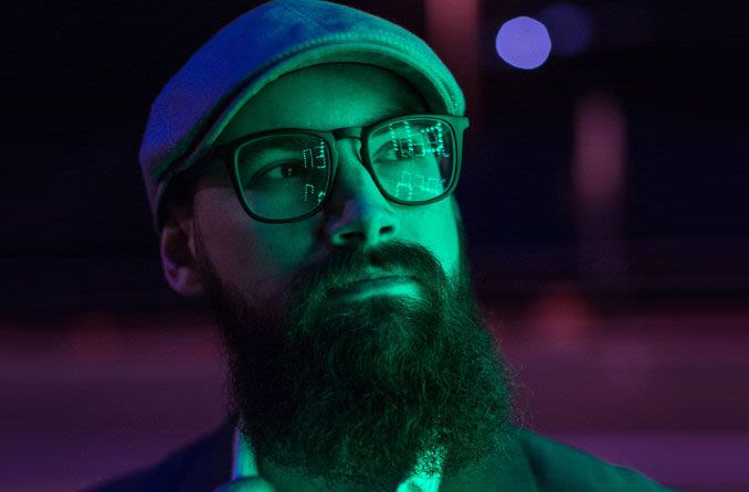 Bearded man wearing hat and glasses at night