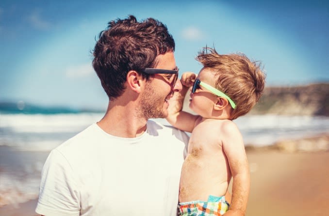 Papa et bébé portant des lunettes de soleil à la plage.