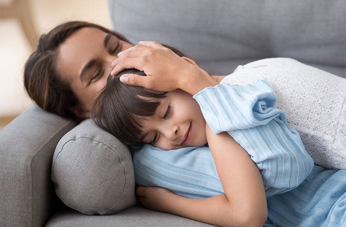 mother and daughter resting their eyes on the sofa at home