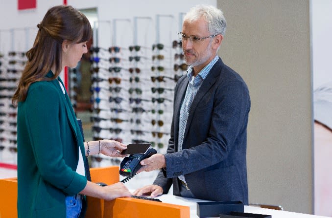 personne dans un magasin de lunettes qui paie ses lunettes