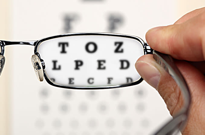 man peering through expired lens in eyeglasses