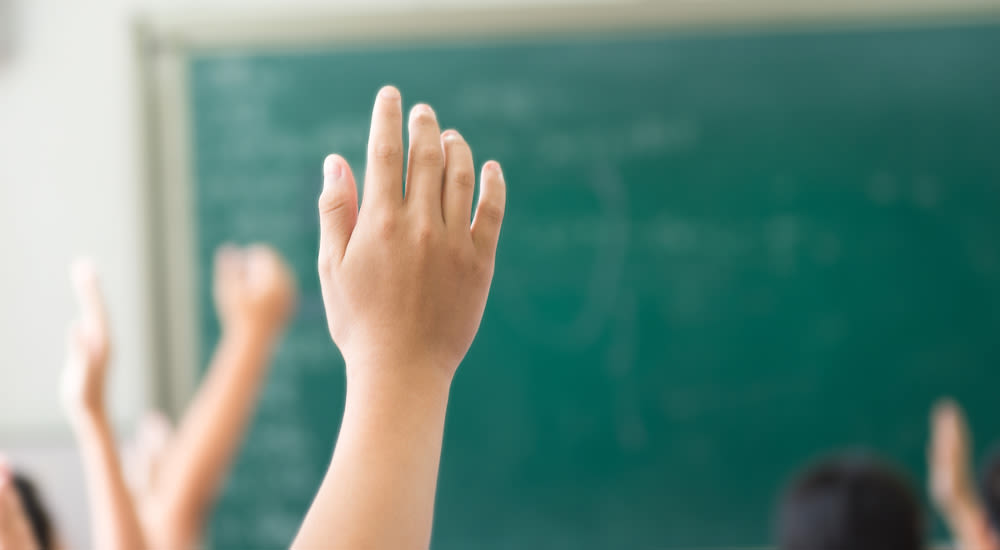 Manos de niños levantadas en clase