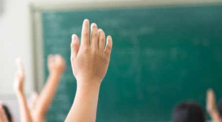 Children's hands raised in class