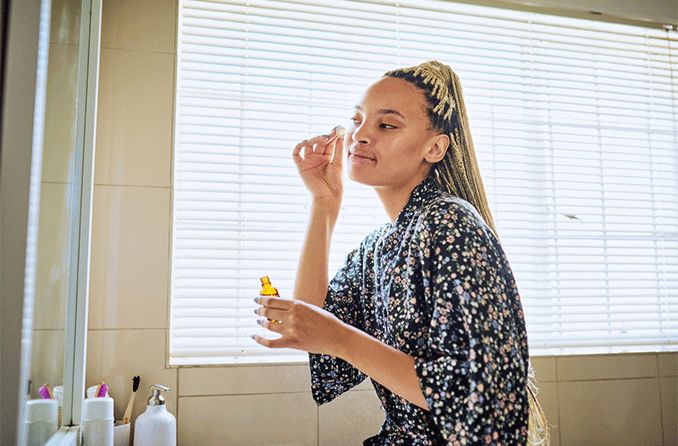 woman putting on face oil near her eyes