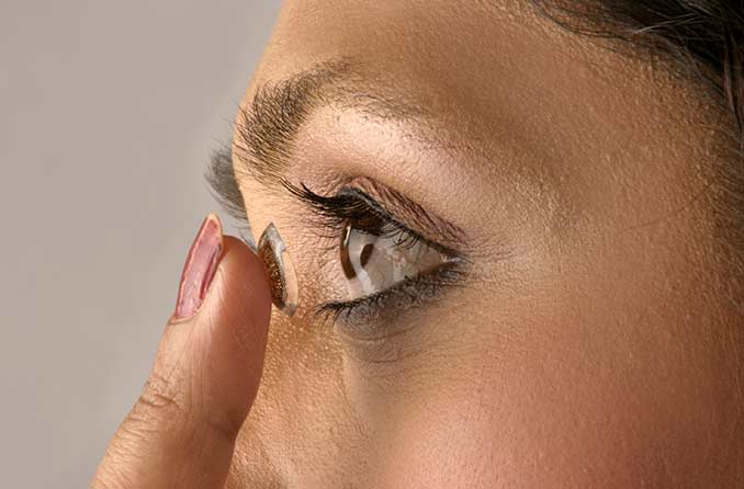 कॉन्टैक्ट लेंस लगाती महिला