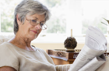 戴眼镜的老妇人在读报纸