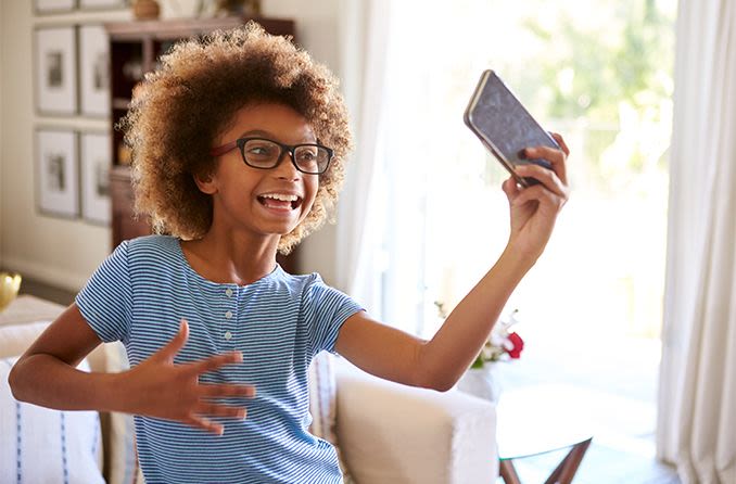 young girl wearing eyeglasses looking at her mobile phone