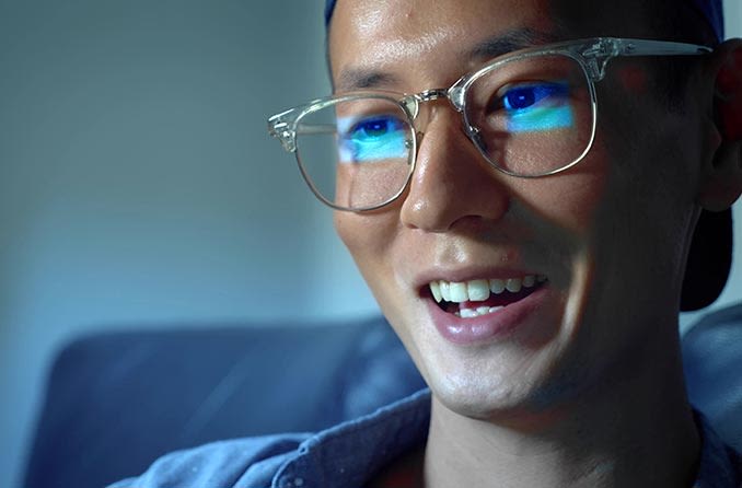 青い光のコンピューターの眼鏡をかけている男