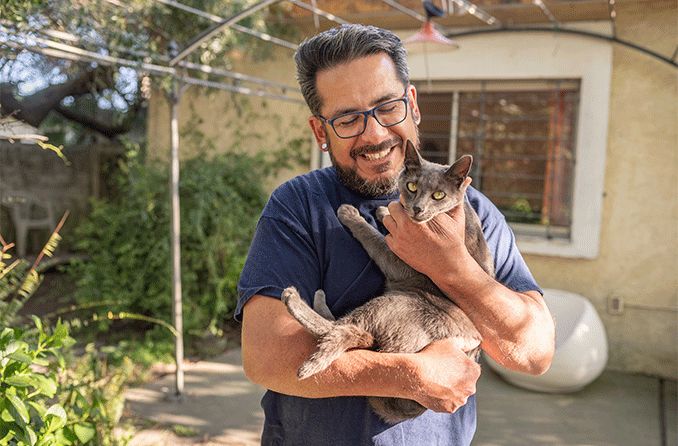 Latino man wearing glasses and holding cat