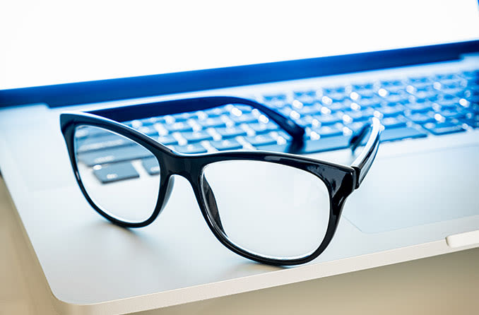 Pair of blue light eyeglasses sitting on a laptop