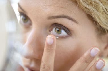 Woman applying contact lens to eye