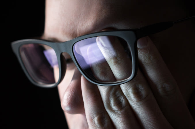  मनुष्य चश्मा पहने हुए कंप्यूटर को देखते हुए अपनी आंख को रगड़ता है।