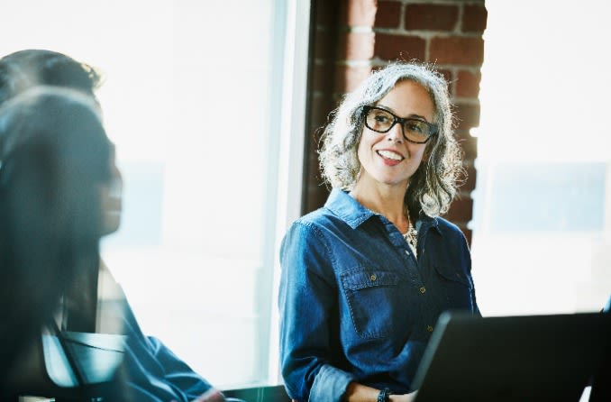 personne souriant à d'autres personnes tout en travaillant sur son ordinateur