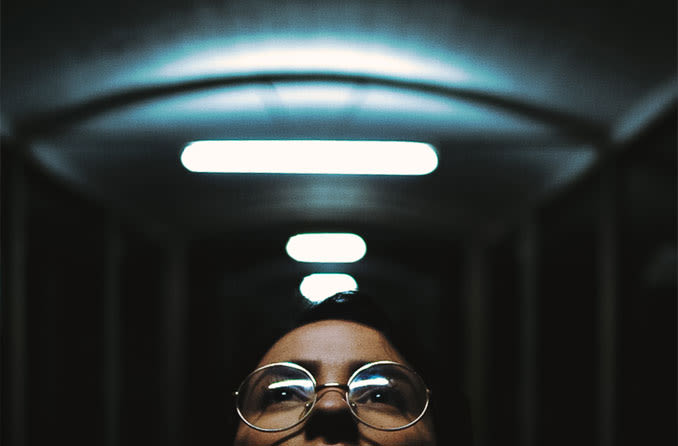woman wearing spectacles looking up at lights