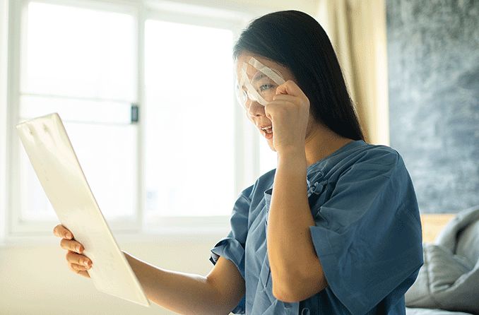 woman with blurry vision holding up something to read after having eye surgery