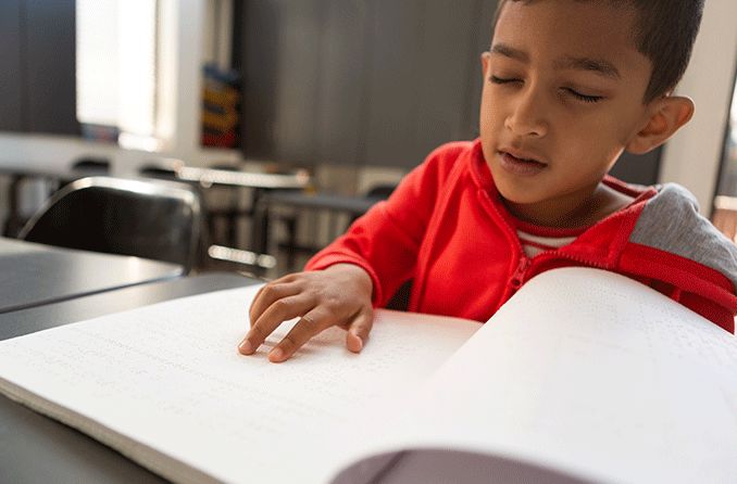 criança cega lendo braille devido a amaurose congênita de Leber