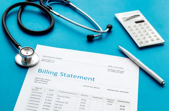 medical bill next to a calculator and stethoscope