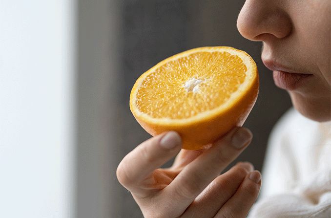 person smelling an orange