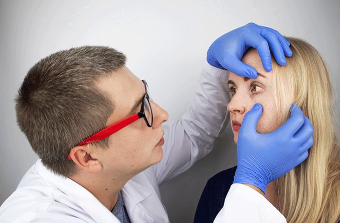 eye doctor looking at woman's eye with corneal erosion