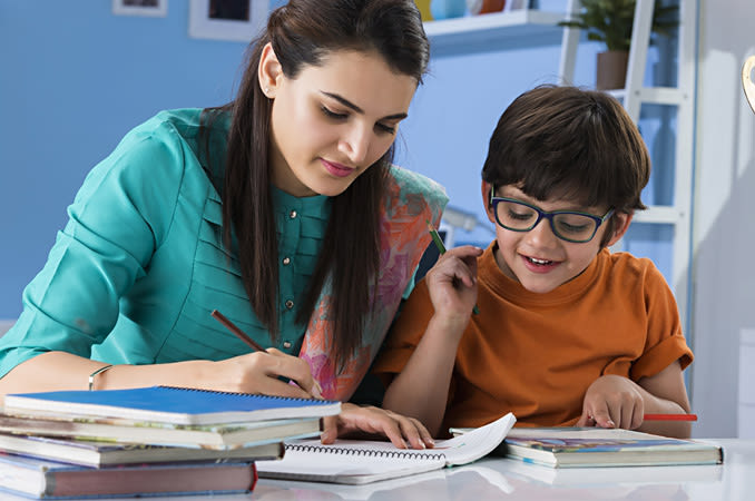 A young boy wearing glasses gets help with his homework.