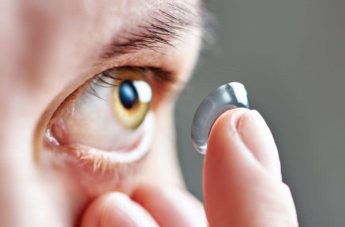 Man applying contact lens to eye