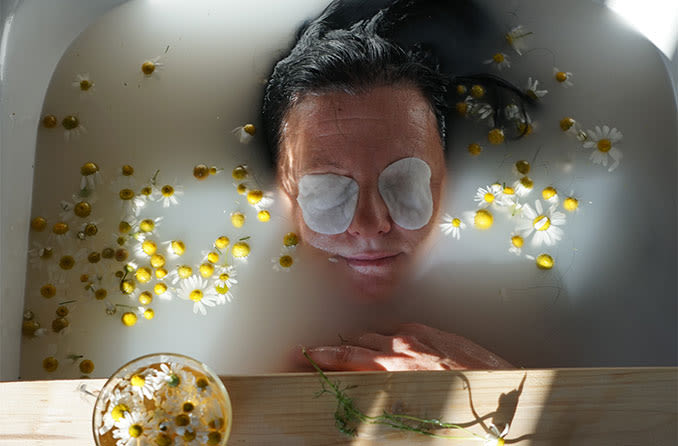 woman relaxing in a tub with compress over her eyes to naturally treat her eye floaters