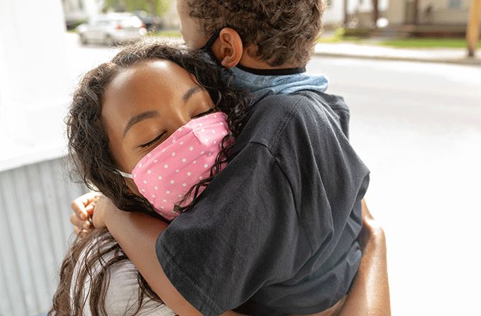 Woman and young child wearing masks and hugging, worried about the covid-19 delta variant