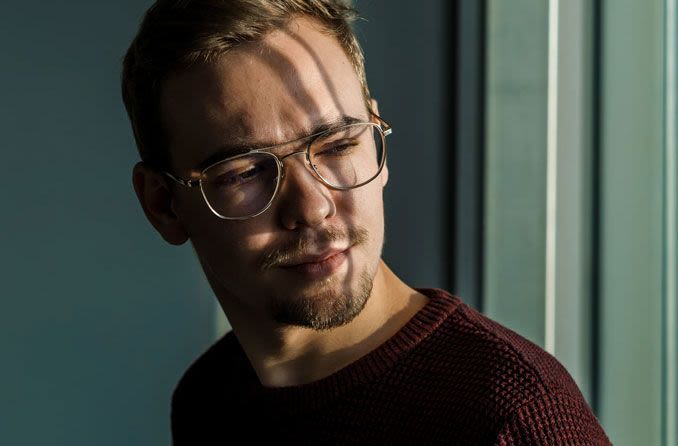 Man wearing glasses, shaded from window