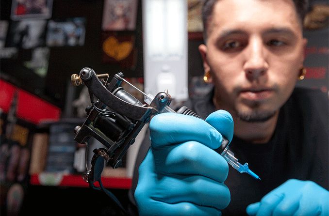 tattoo artist holding needle getting ready for eye tattoo