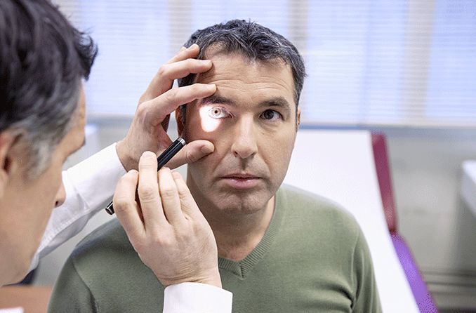 eye doctor performing a perrla eye test on patient