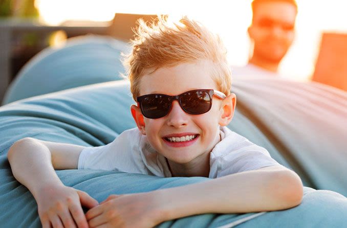 Smiling boy wearing sunglasses.