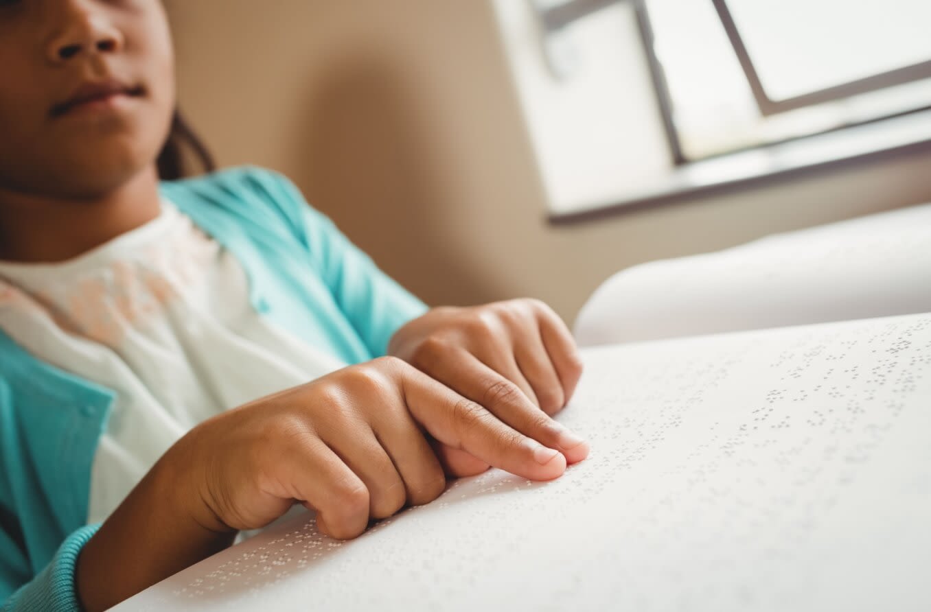 Girl using braille to read at school.