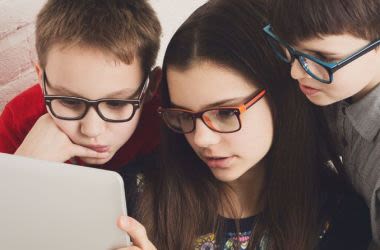 Three children wearing glasses looking at computer screen