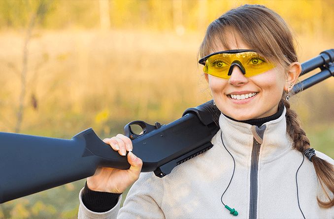 woman wearing shooting glasses and holding gun