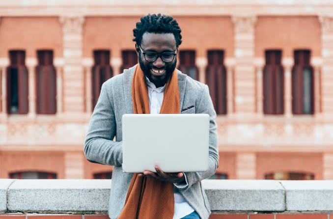 personne souriante à l'extérieur avec un ordinateur portable