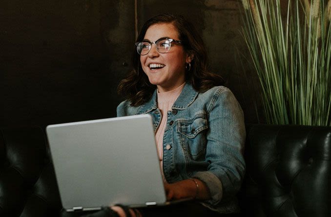 手提电脑上戴着眼镜的快乐女人，FSA