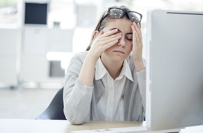 mulher um computador esfregando os olhos cansados