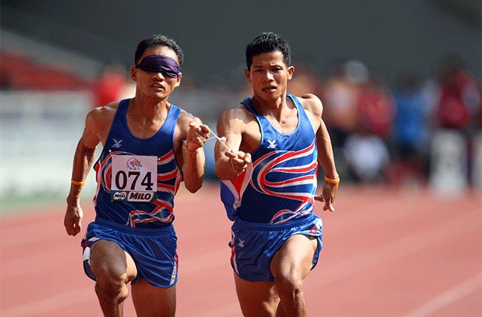 Thailand's blind athlete Kitsana Jorchuy runs with a guide at the track and field event