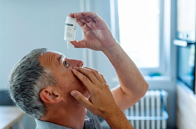 Hombre poniendo gotas para los ojos en sus ojos secos