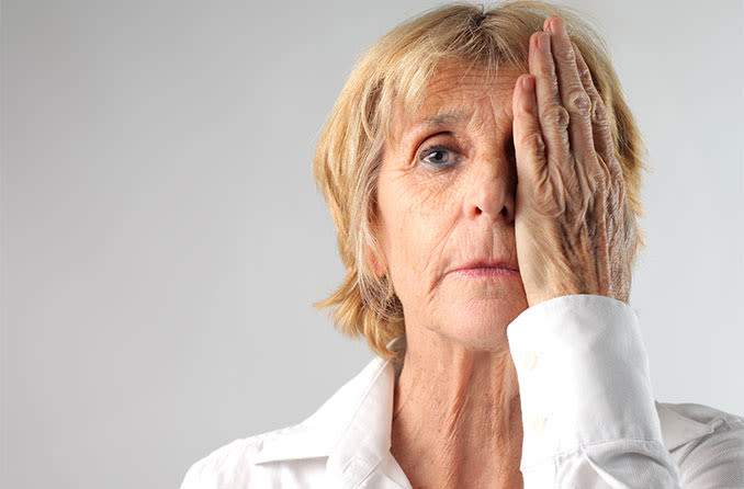 woman with one hand over her eye taking a visual acuity test for cataracts