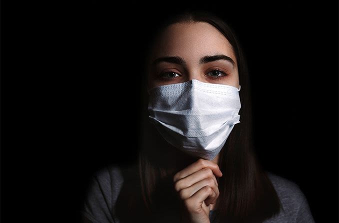 Mulher usando máscara branca para se proteger do coronavírus

