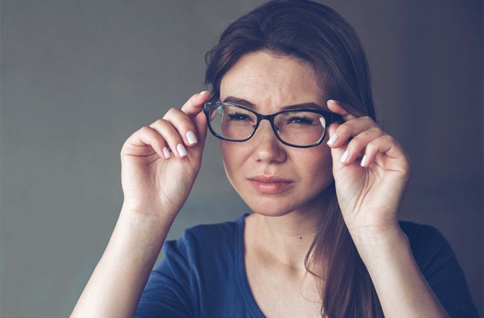 woman squinting through her glasses with both astigmatism and myopia