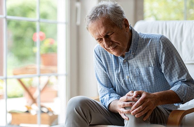 older man with rheumatoid arthritis squinting in pain