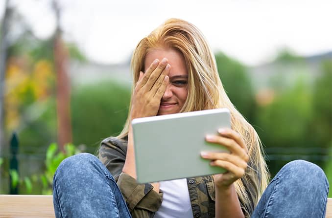 woman with astigmatism squinting to read her tablet
