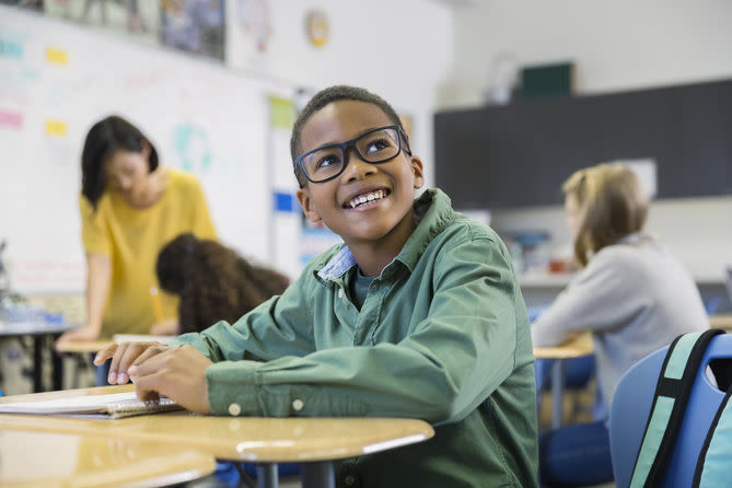 enfant souriant portant des lunettes dans une salle de classe