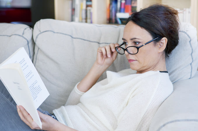 Женщина в очках читает книгу